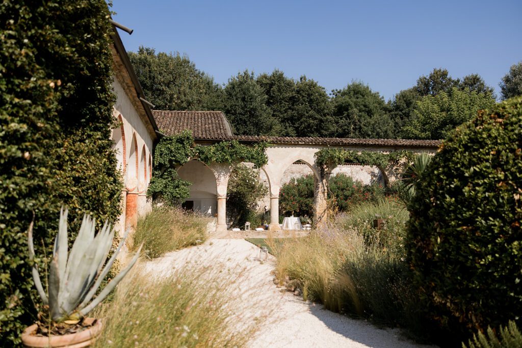 Italiano: Convento dell'Annunciata di Medole — location per matrimoni esclusivi in Lombardia: il porticato ad archi con vegetazione rampicante e il giardino con viale in ghiaia